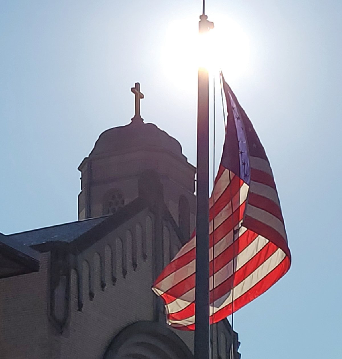 LOOMING SYMBOLS: The American flag flapped high above the crowd gathered outside St. Rocco School for last Friday’s “Prayer for Peace and Healing on the 20th Anniversary of 9/11.”